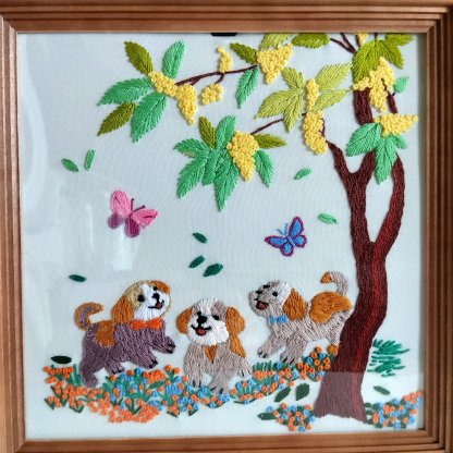 Puppies in a blooming garden. Picture, embroidery, satin stitch.